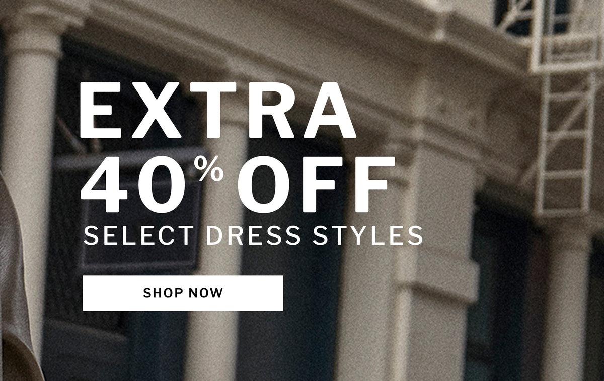 Promotional banner with large white text reading 'EXTRA 40% OFF SELECT DRESS STYLES' and a 'SHOP NOW' button over a blurred building facade background.