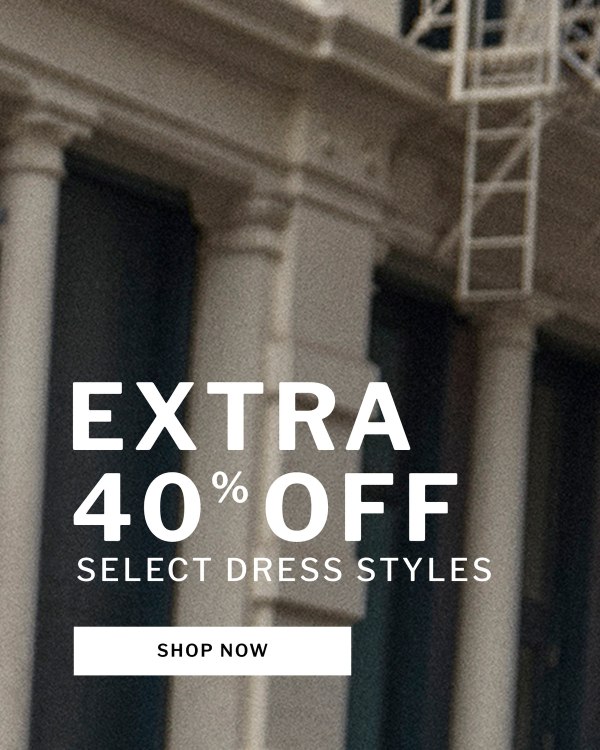 Promotional graphic with large white text reading 'EXTRA 40% OFF SELECT DRESS STYLES' and a 'SHOP NOW' button over a blurred architectural background with columns and a fire escape.